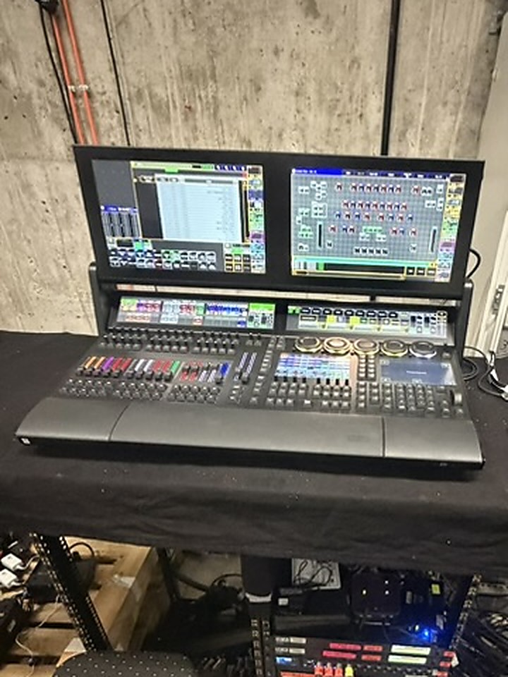 Mischpult mit zwei Monitoren auf Regietisch neben Technikrack